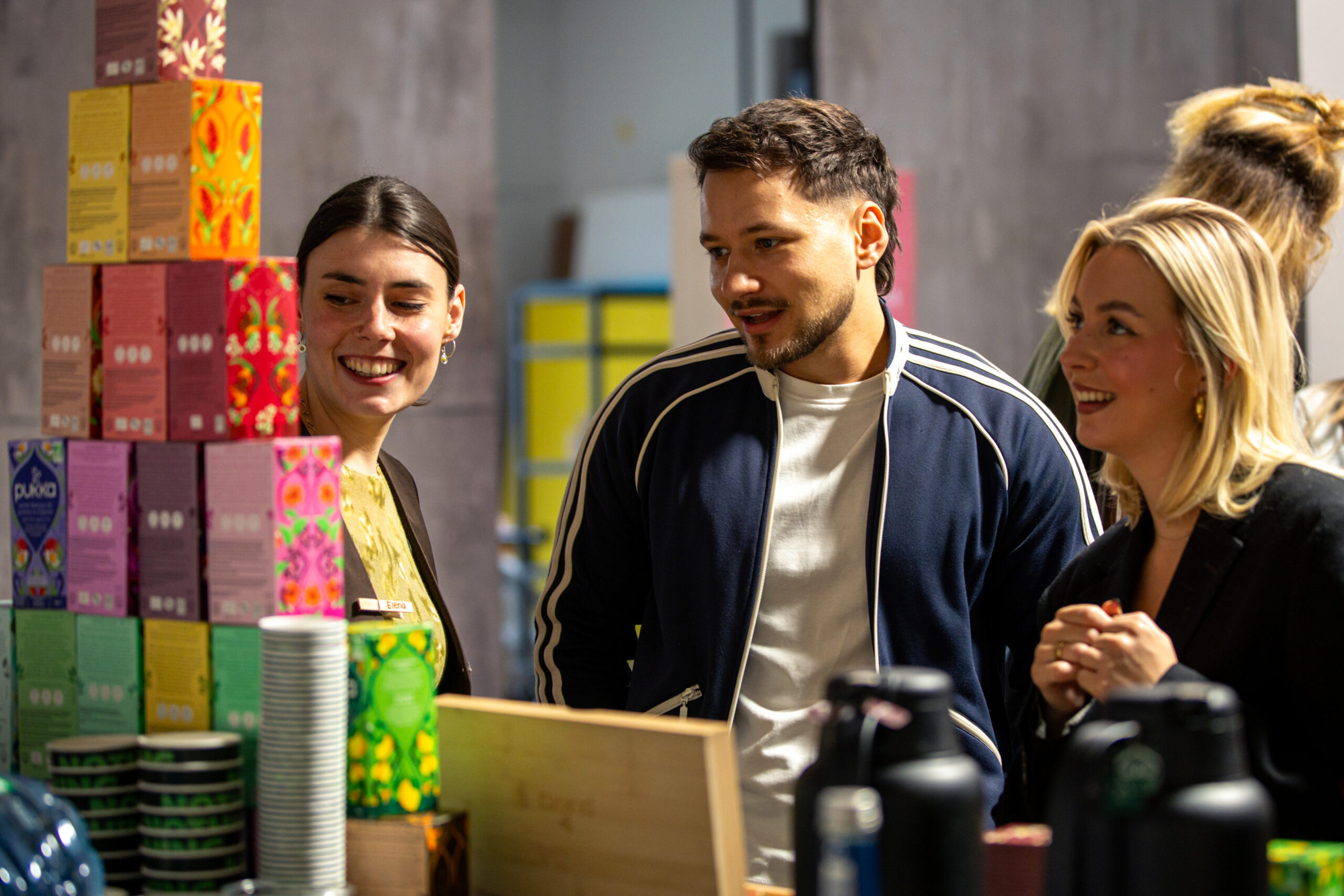 Drei Personen schauen auf eine Pyramide gebaut aus Pukka Herbs Teeboxen beim Influencer Event